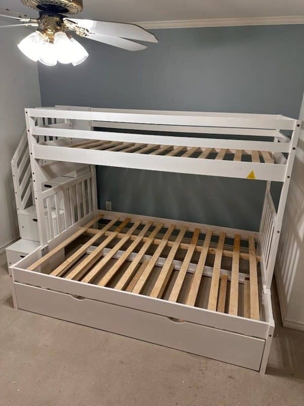 White bunk bed with a staircase end and a pull-out trundle in a kids' room