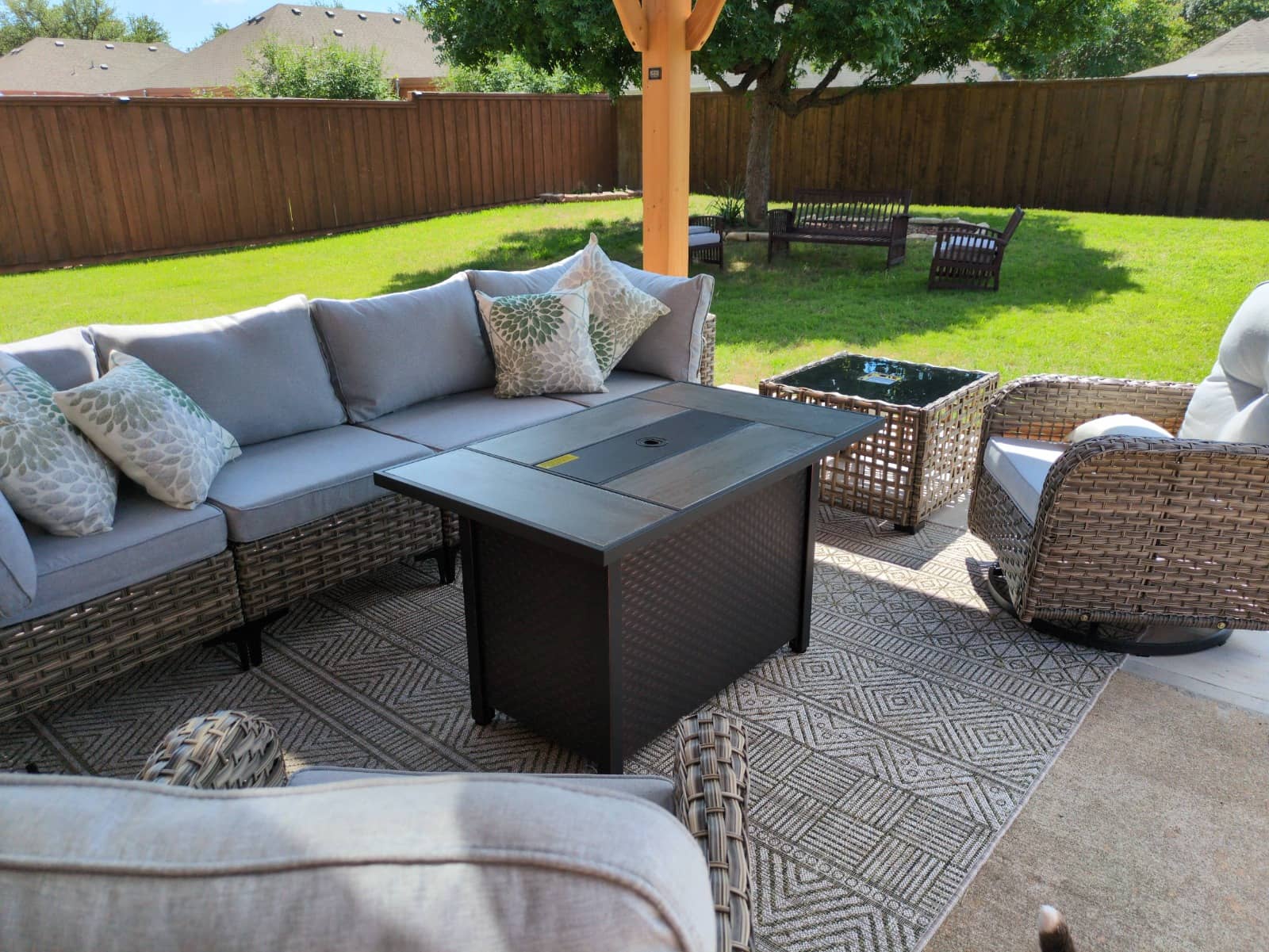 Wicker patio sectional and a fire-pit table assembled on a backyard patio