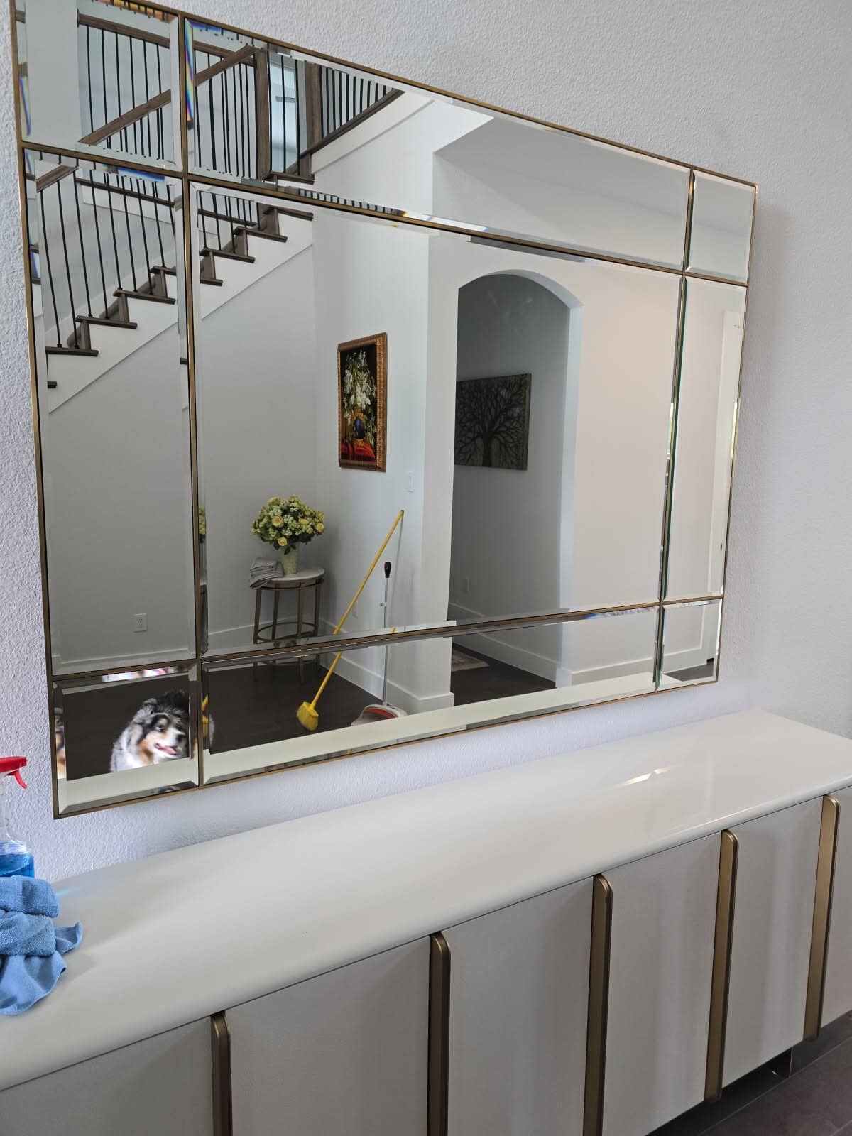 Large beveled mirror with a thin brass frame hung above a white sideboard
