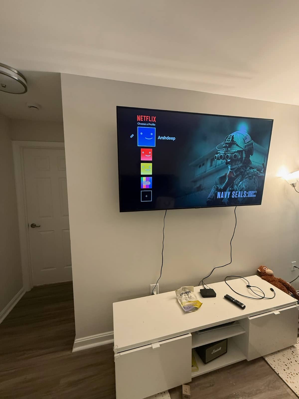 Flat-screen TV mounted on a living room wall above a low white media console