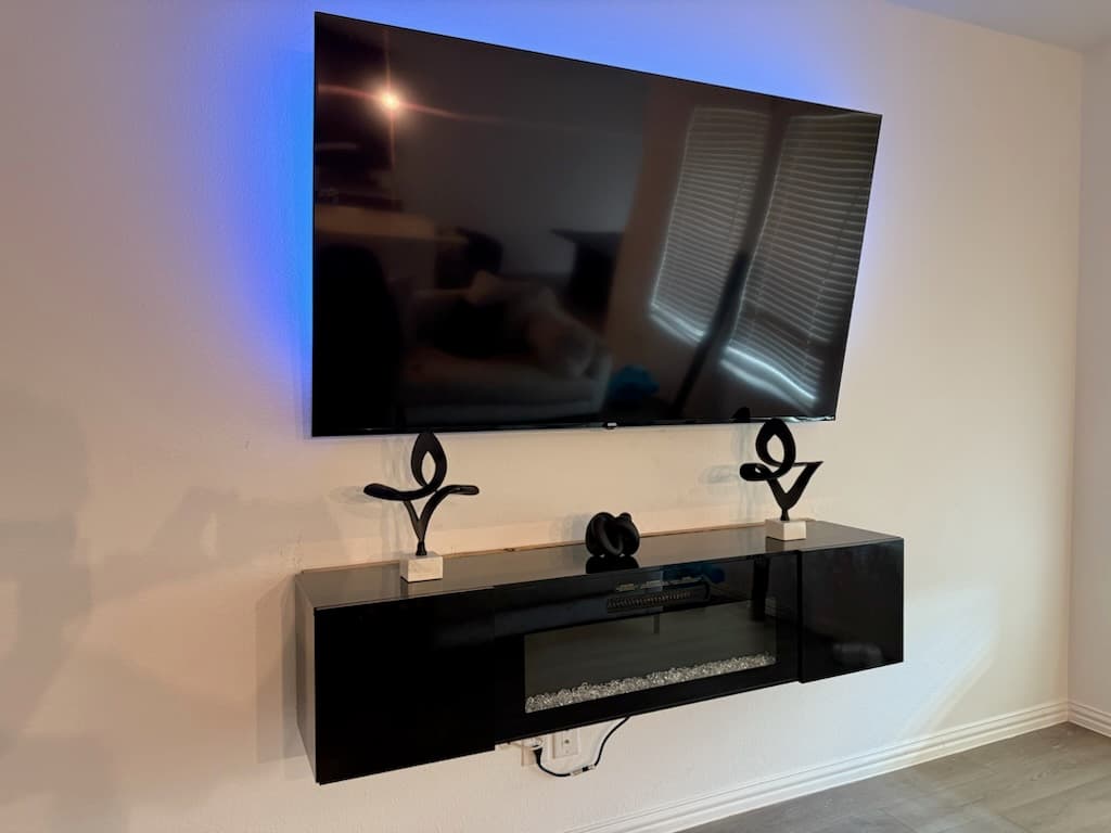 Flat-screen TV mounted level above a floating shelf in a living room