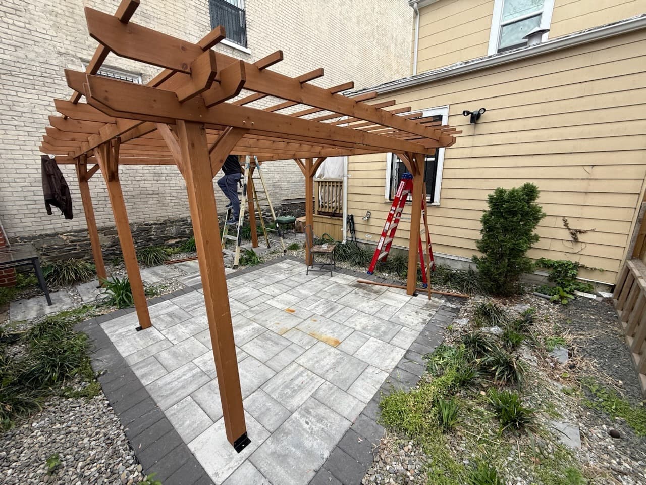 Cedar pergola frame going up over a new paver patio