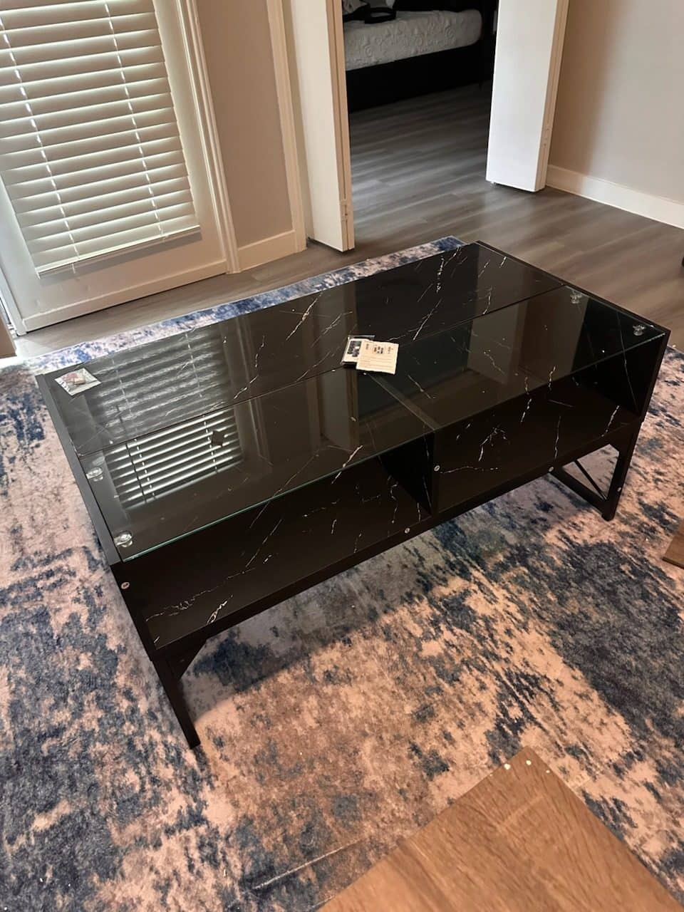Black marble-look coffee table with a glass top assembled on a patterned rug