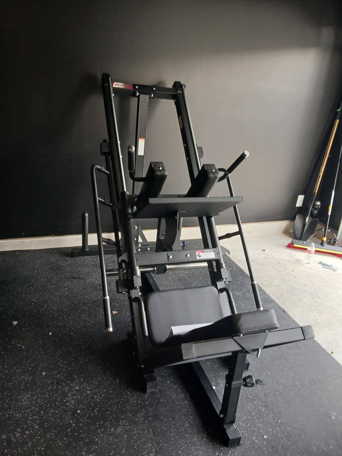 Plate-loaded leg press and hack squat machine assembled on rubber flooring