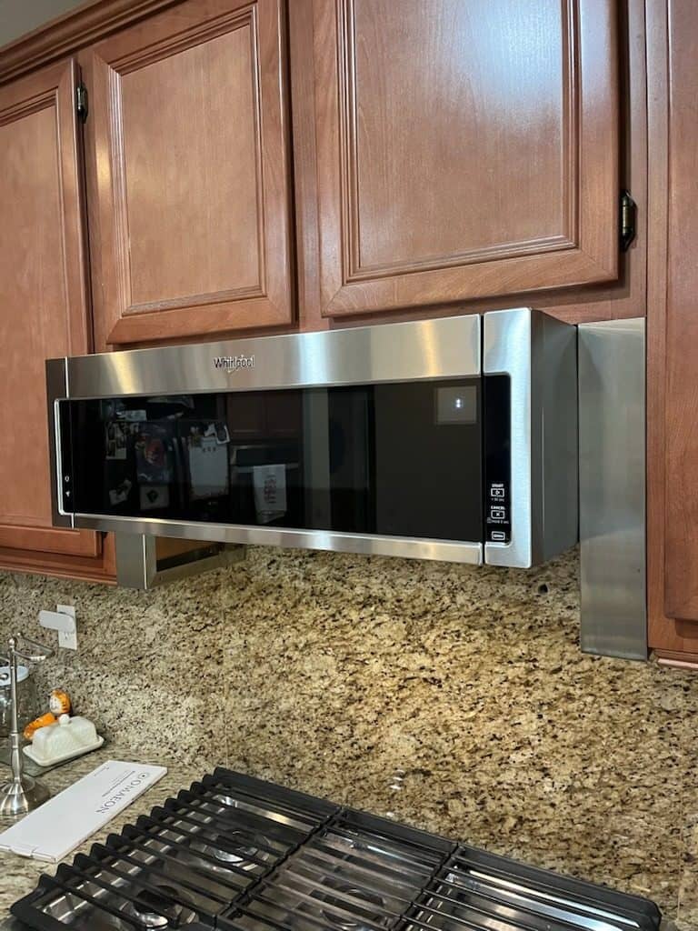 Stainless over-the-range microwave installed under wood cabinets