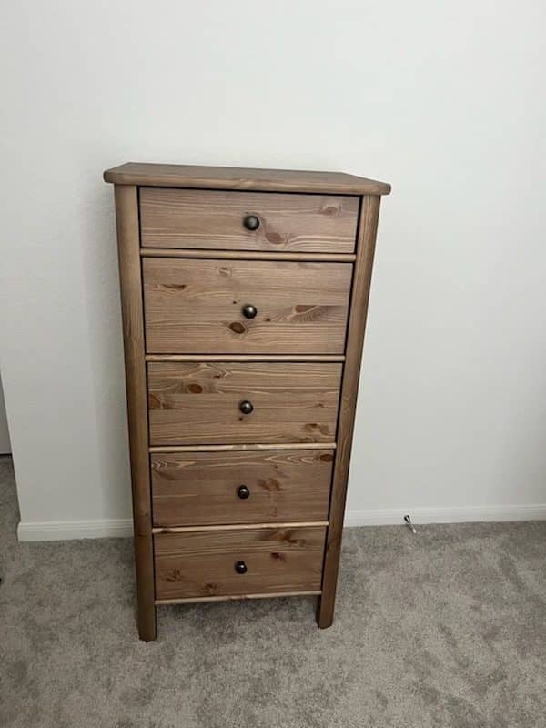 Tall five-drawer wooden chest assembled and standing on carpet
