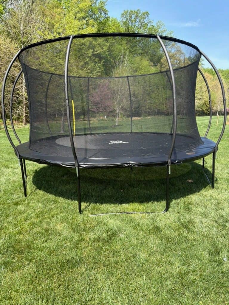 Large round trampoline with a curved-pole safety enclosure on a mown lawn