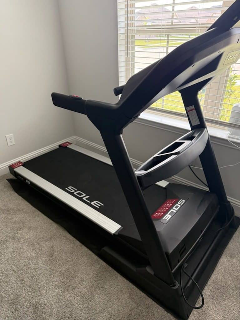 Folding treadmill assembled on carpet in front of a bedroom window