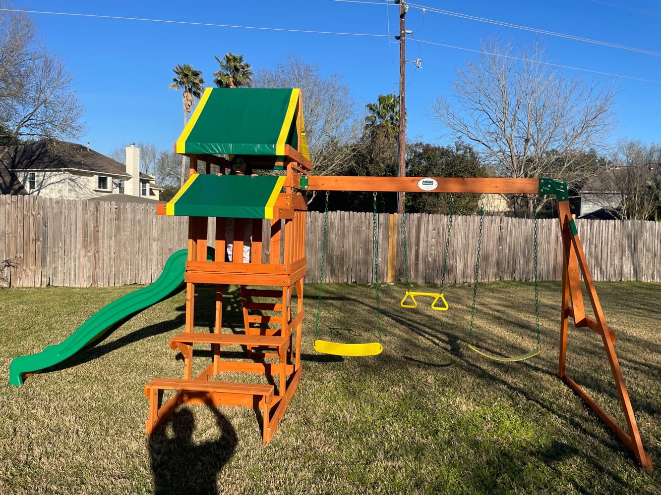 Wooden backyard playset with a green canopy, assembled in Frisco